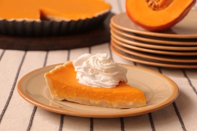 Photo of Piece of fresh homemade pumpkin pie with whipped cream on table