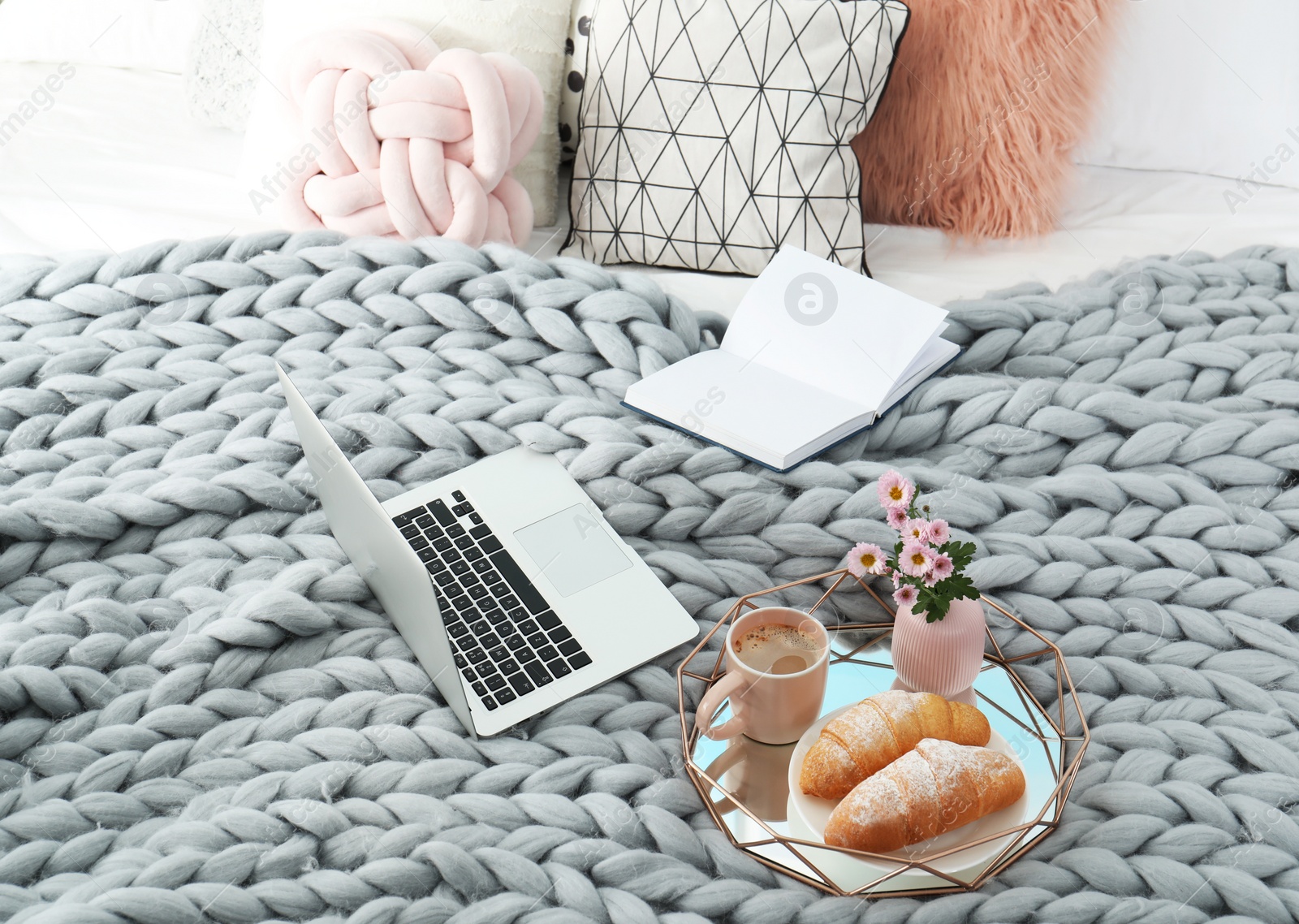 Photo of Tray with tasty breakfast, laptop and book on bed
