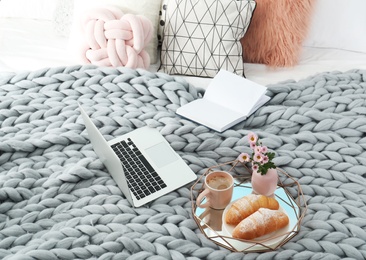 Tray with tasty breakfast, laptop and book on bed