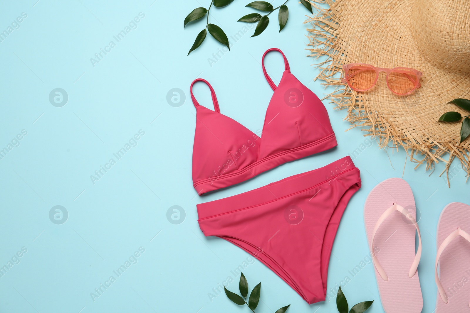 Photo of Stylish bikini and beach accessories on light blue background, flat lay. Space for text