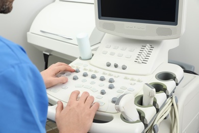 Photo of Sonographer operating modern ultrasound machine in clinic, closeup