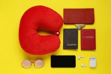 Photo of Flat lay composition with red travel pillow and smartphone on yellow background