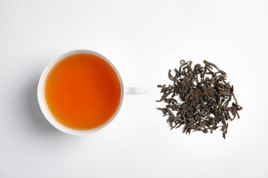 Photo of Cup of delicious tea with dried leaves on light background, top view