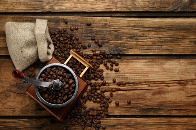 Vintage manual coffee grinder and beans on wooden table, flat lay. Space for text