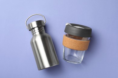 Photo of Eco friendly bottle and cup on lavender background, flat lay. Conscious consumption