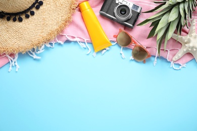 Flat lay composition with beach accessories on light blue background, space for text