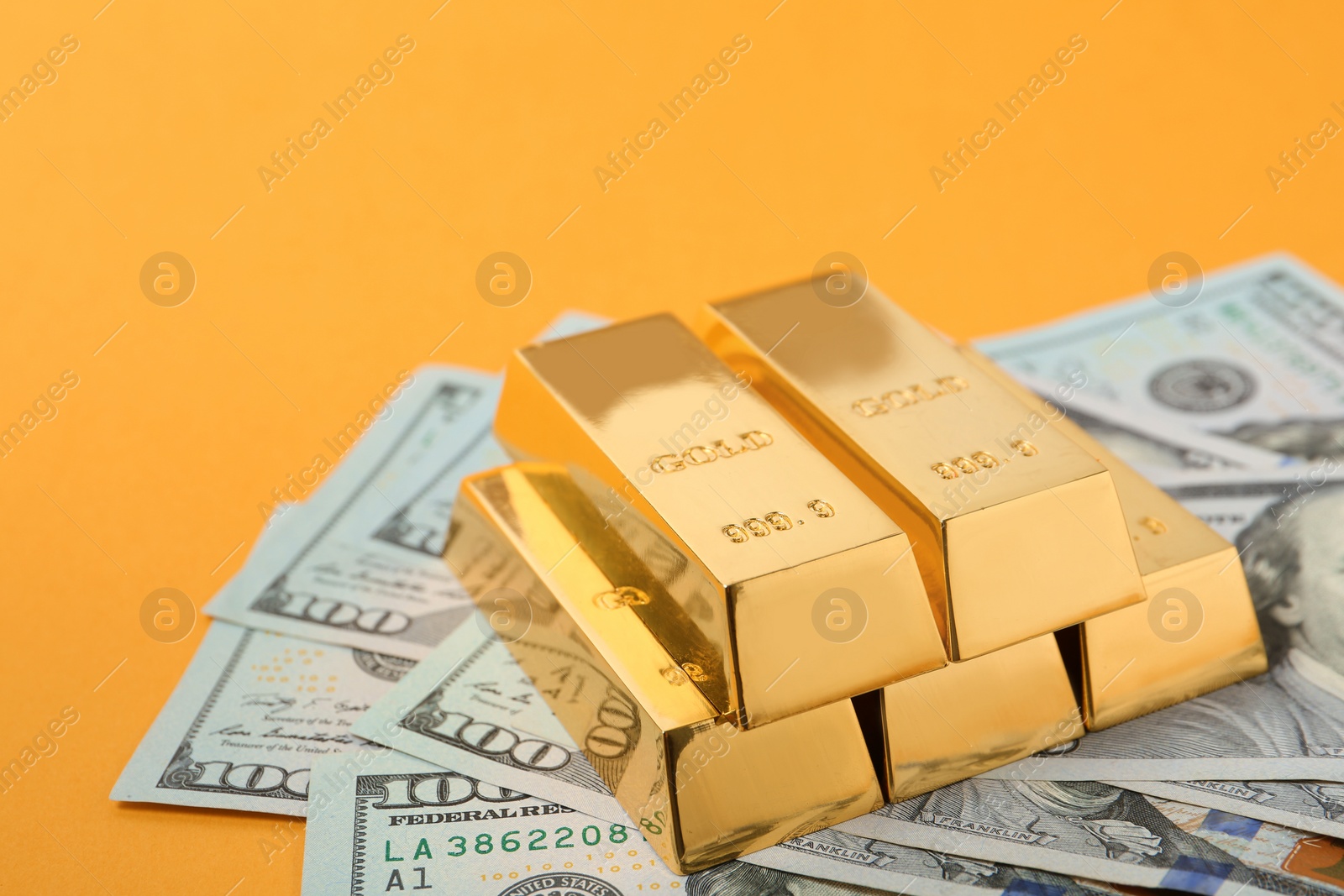 Photo of Shiny gold bars and dollar bills on color background