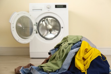 Pile of dirty laundry near washing machine indoors