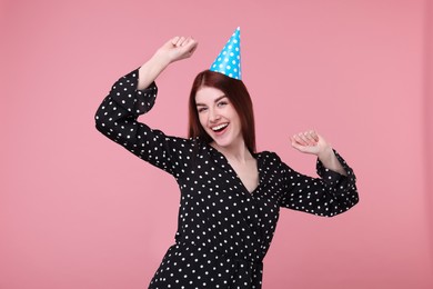 Happy woman in party hat on pink background