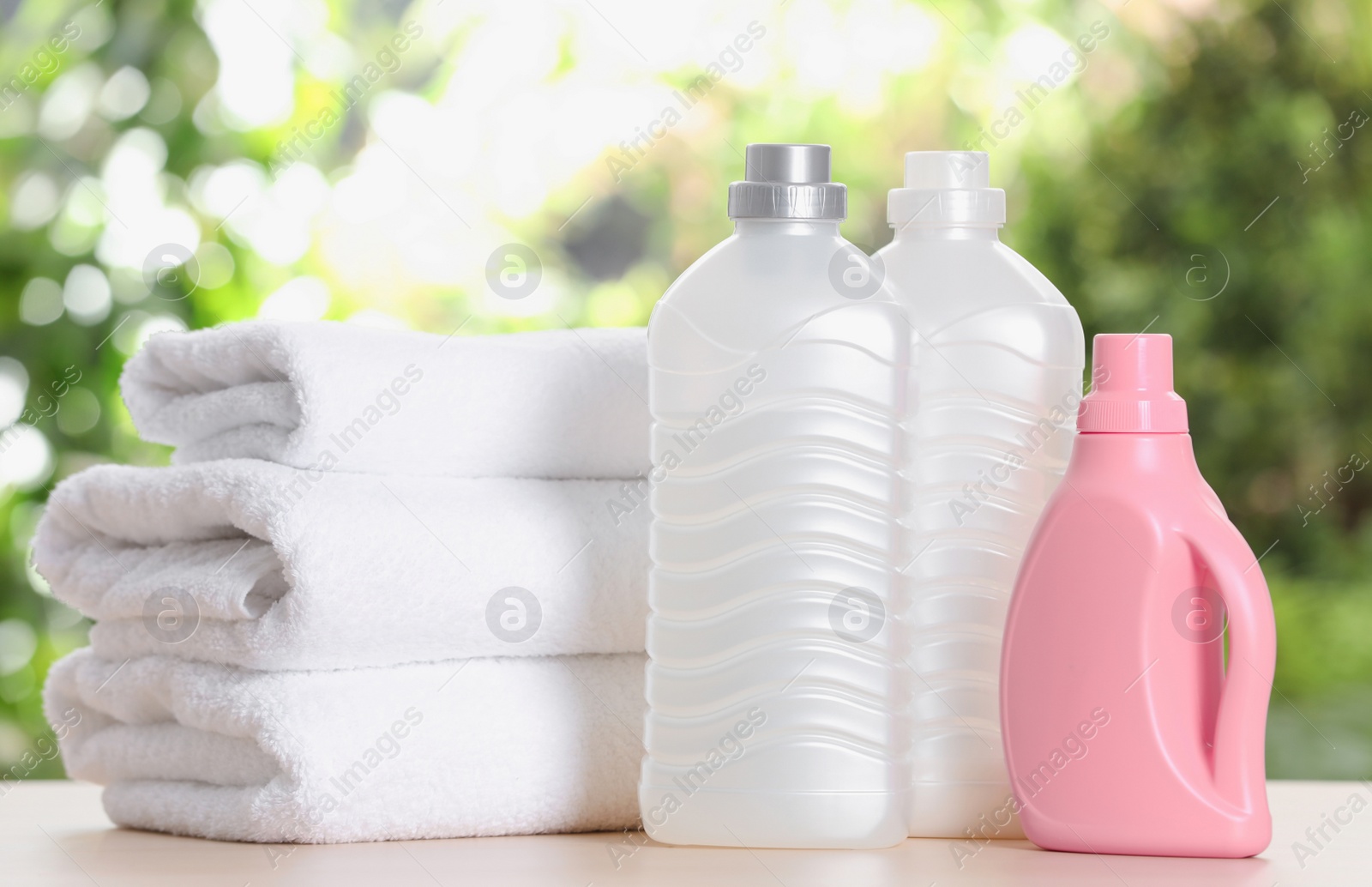 Photo of Soft bath towels and laundry detergents on table against blurred background