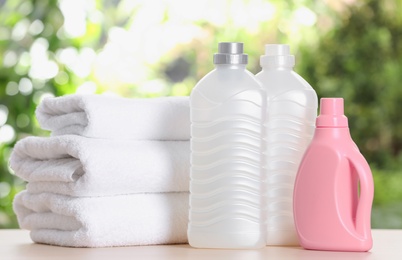 Soft bath towels and laundry detergents on table against blurred background