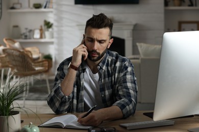 Man talking on phone while working at table in home office