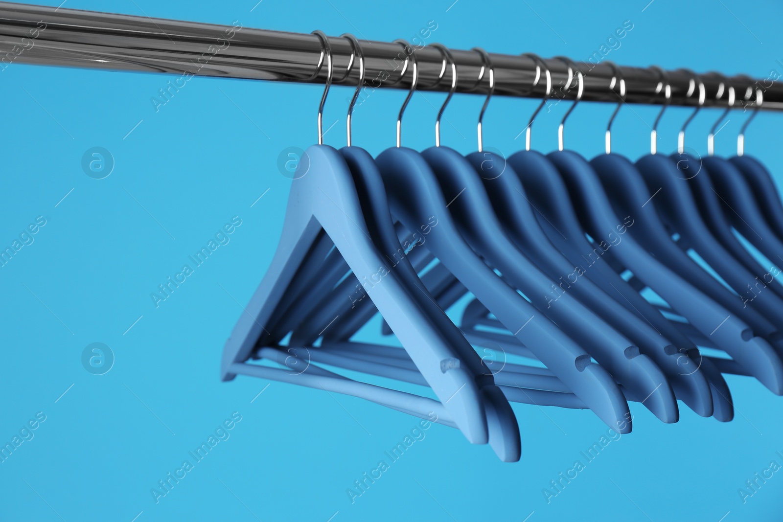 Photo of Metal rack with clothes hangers on color background