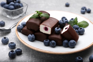 Photo of Delicious glazed curd snacks with fresh blueberries and mint on light grey table
