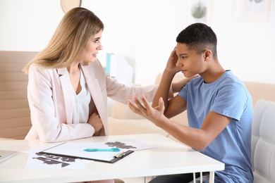 Female psychologist working with African American teenage boy in office