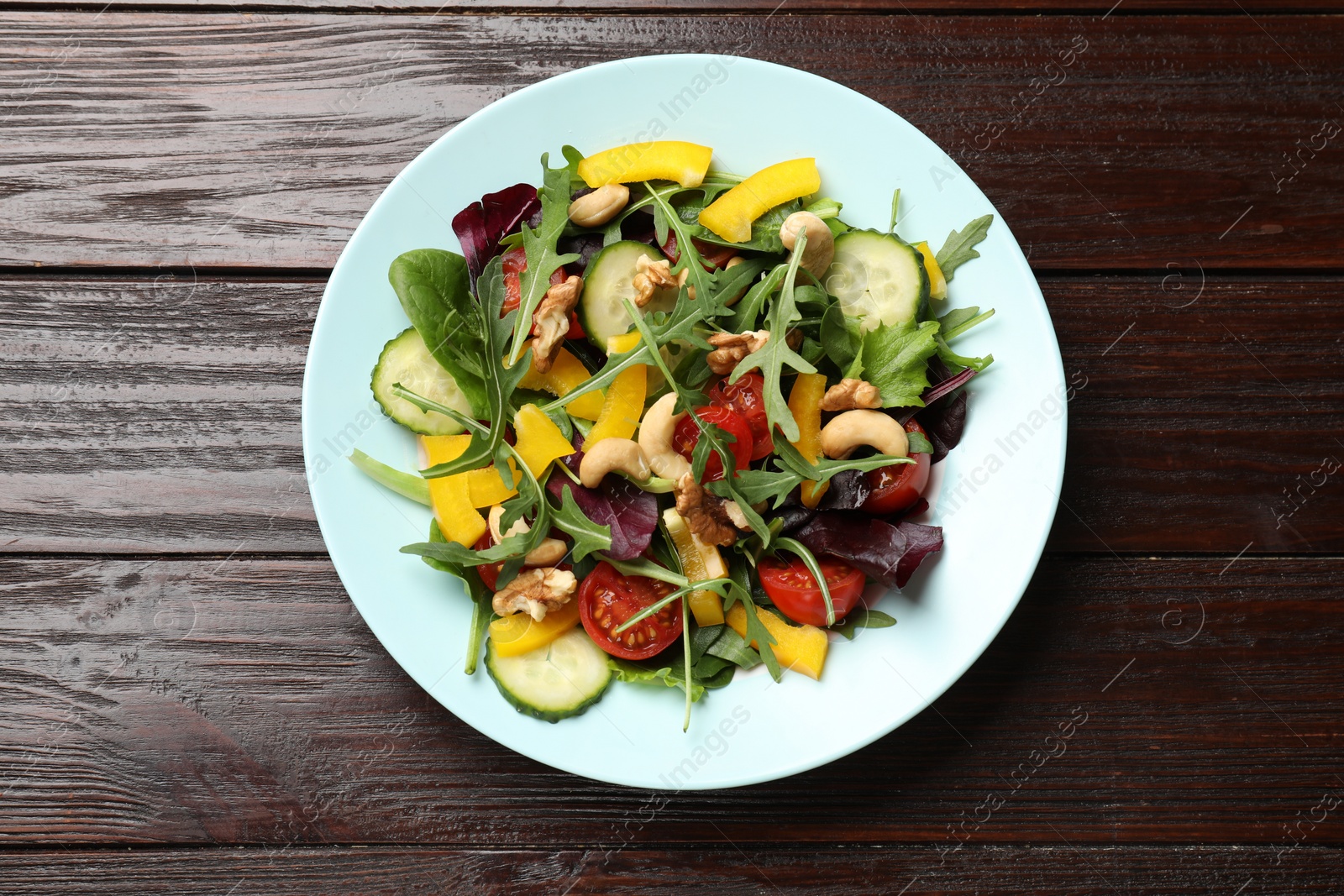 Photo of Tasty fresh vegetarian salad on dark wooden table, top view