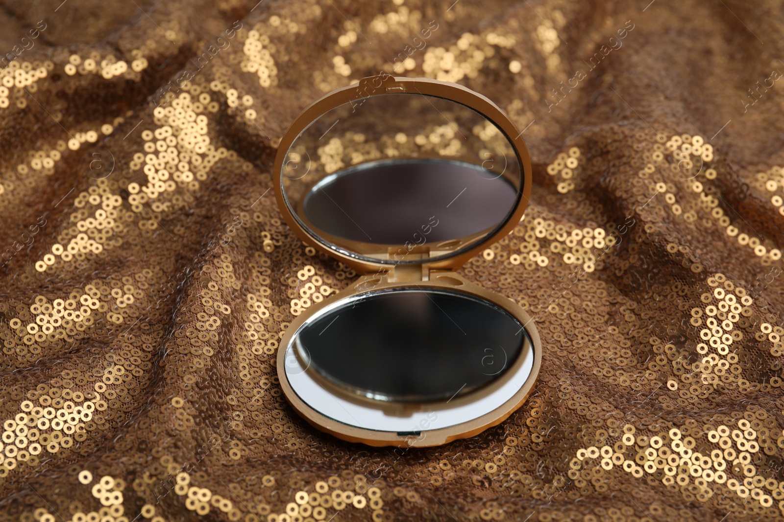 Photo of Bright cosmetic pocket mirror on gold fabric