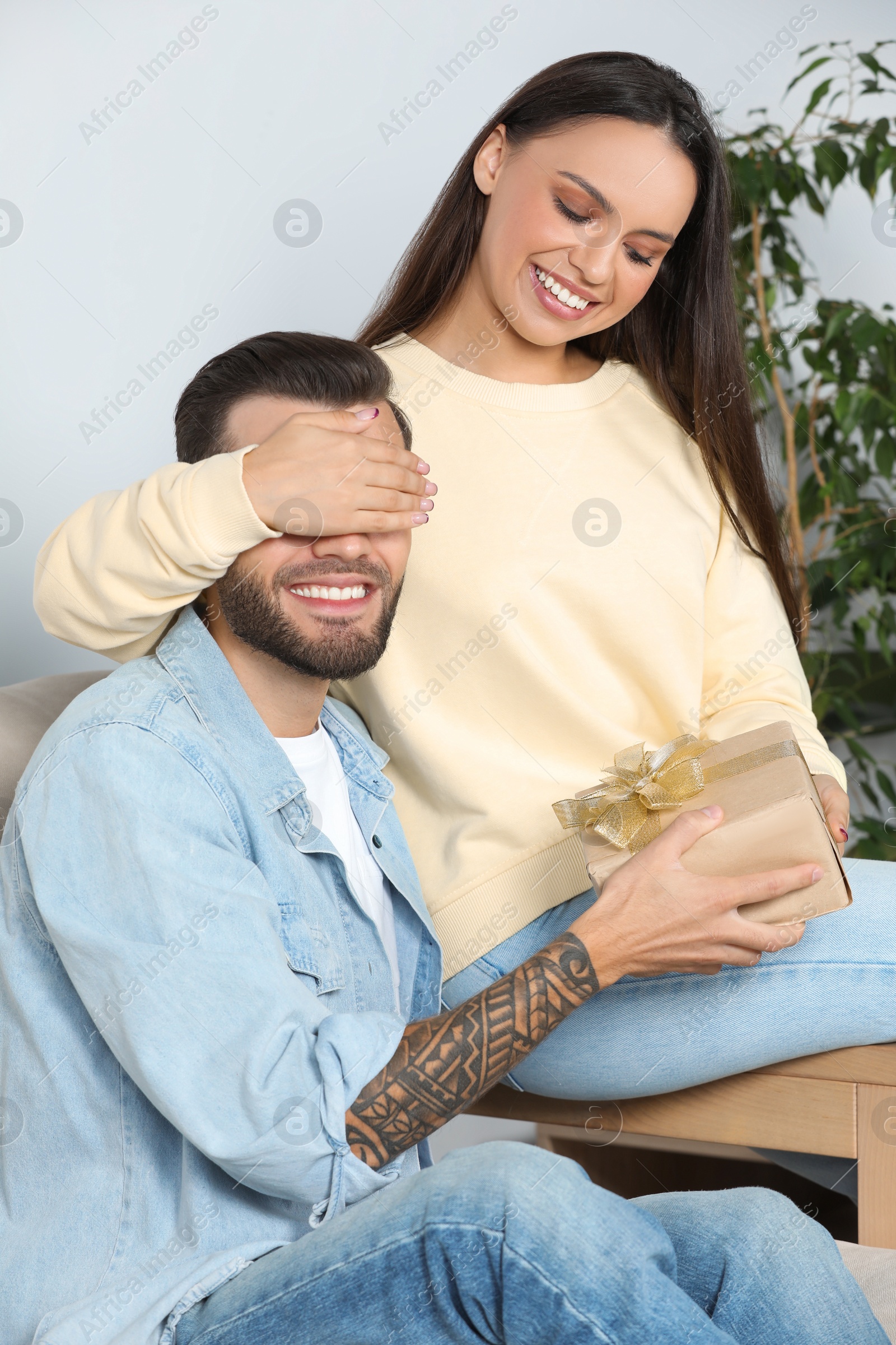 Photo of Woman presenting gift to her boyfriend at home