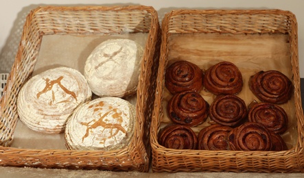 Photo of Wicker trays with fresh bread and buns in bakery store