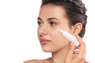 Photo of Woman applying cream under eyes on white background, closeup. Skin care