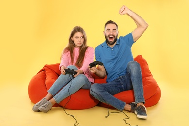 Photo of Emotional couple playing video games with controllers on color background