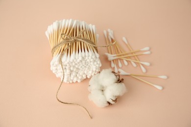 Photo of Many cotton buds and flower on beige background