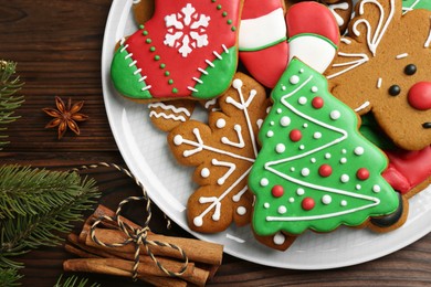 Different tasty Christmas cookies, spices and fir tree branch on wooden table, flat lay