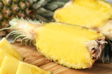 Photo of Cut fresh juicy pineapple on wooden board, closeup