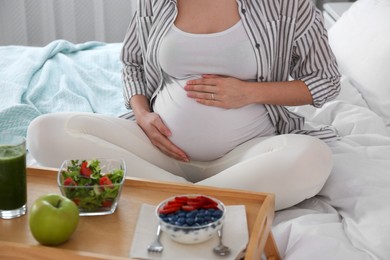 Photo of Pregnant woman with breakfast on bed, closeup. Healthy diet