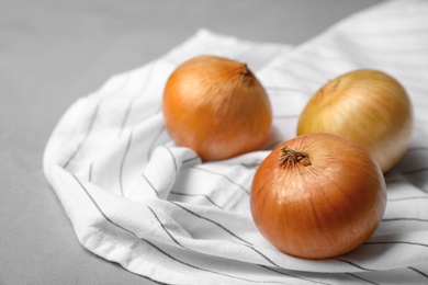 Photo of Fabric with ripe onions on grey table, space for text