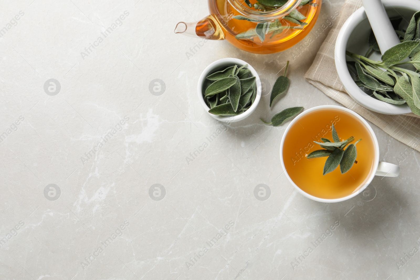 Photo of Sage tea and green leaves on light grey marble table, flat lay. Space for text