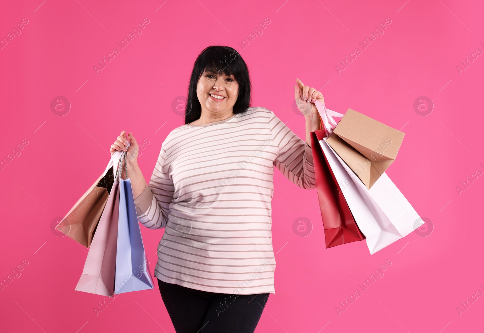 Photo of Beautiful overweight mature woman with shopping bags on pink background