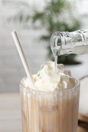 Photo of Pouring syrup into glass of tasty iced coffee, closeup