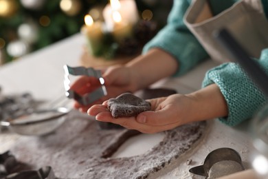 Photo of Little child making Christmas cookies at white table, closeup