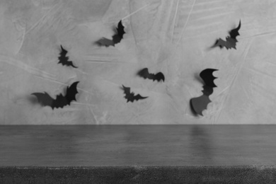 Photo of Stone table near grey wall with black paper bats. Halloween decoration