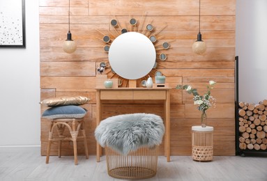 Dressing table with decor near wooden wall in room
