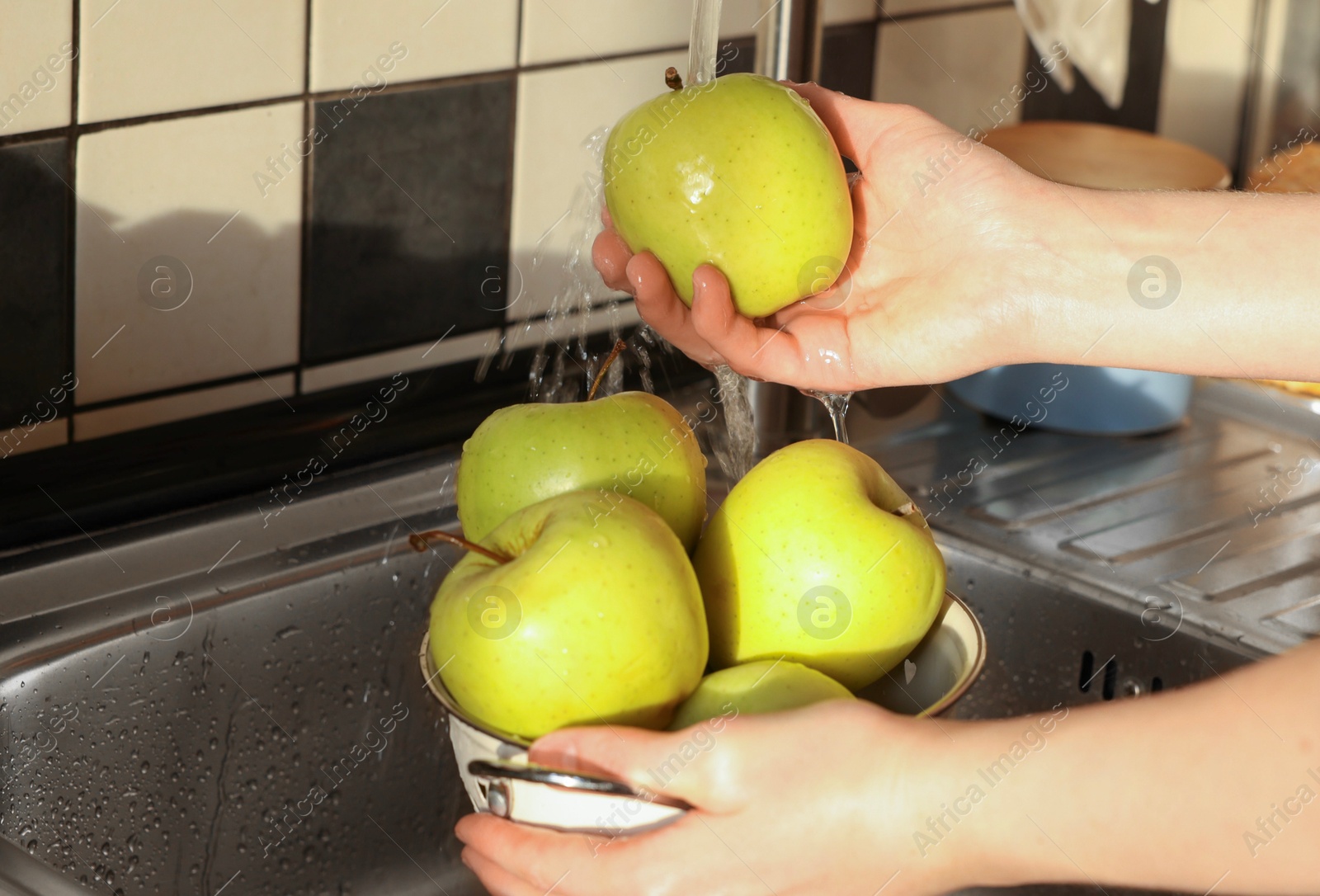 Photo of Woman washing fresh apples in metal colander, closeup