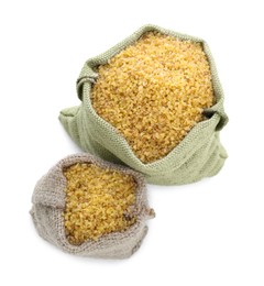 Burlap bags with uncooked bulgur on white background, closeup