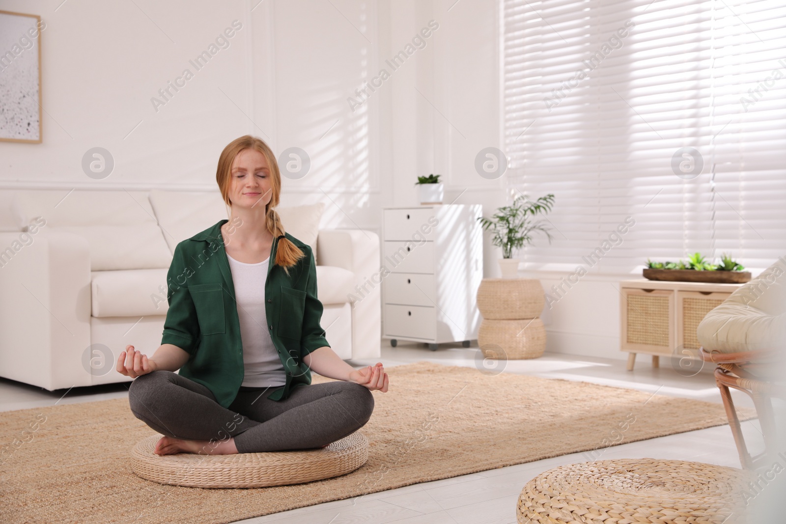 Photo of Woman meditating on wicker mat at home. Space for text