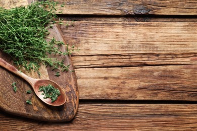 Photo of Bunch of aromatic thyme on wooden table, top view. Space for text