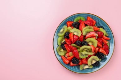 Plate of yummy fruit salad on pink background, top view. Space for text