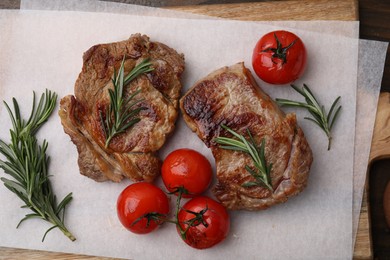 Delicious fried meat with rosemary and tomatoes on wooden board, flat lay