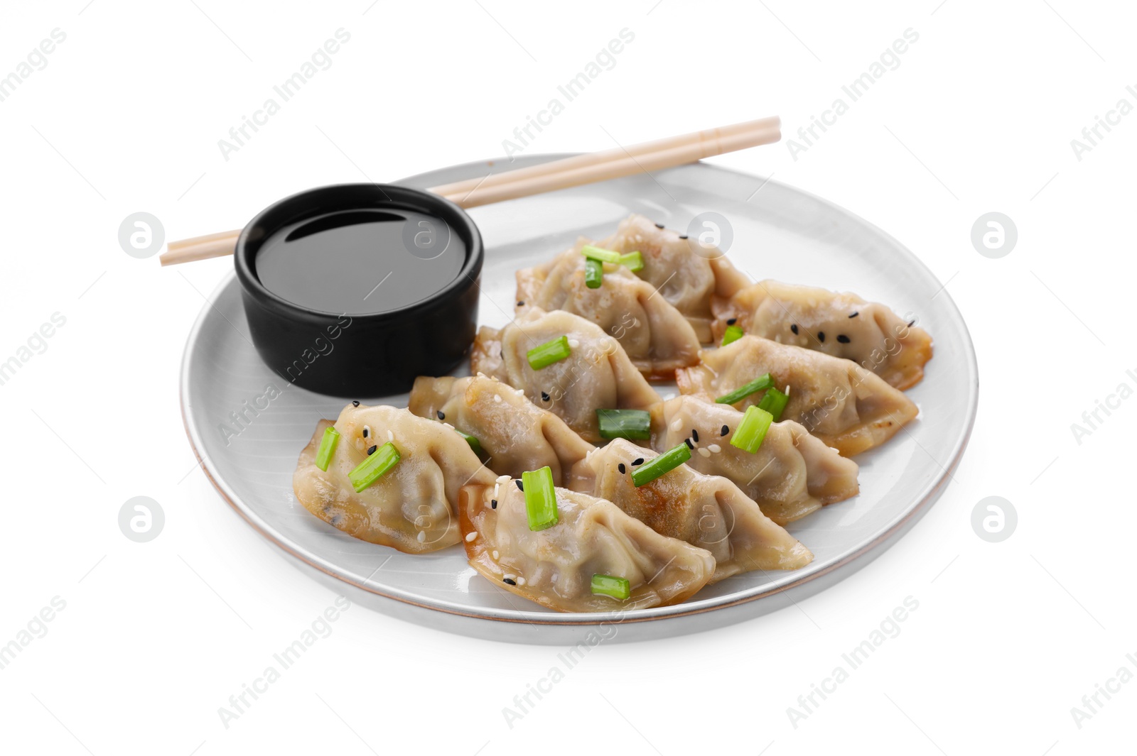 Photo of Delicious gyoza (asian dumplings) with green onions, soy sauce and chopsticks isolated on white