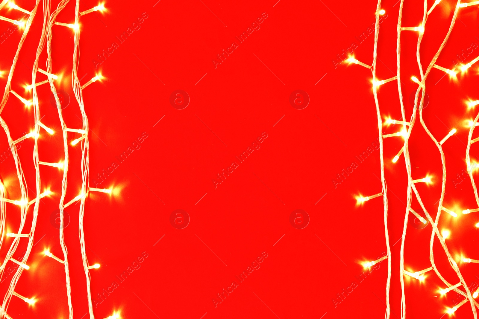 Photo of Christmas lights on red background, top view. Space for text