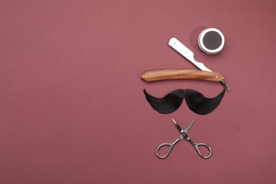 Photo of Artificial moustache and barber tools on burgundy background, flat lay. Space for text