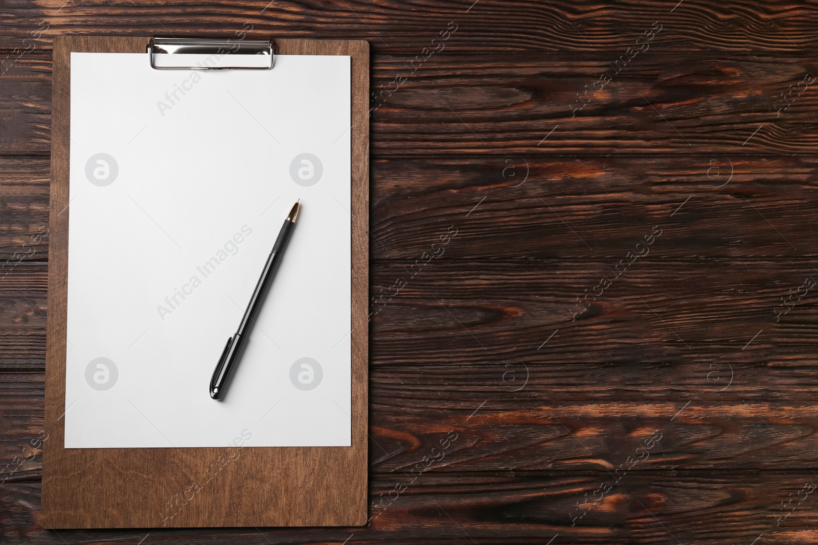 Photo of New clipboard with sheet of blank paper and pen on wooden table, top view