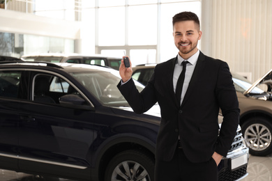 Salesman with key in modern car salon