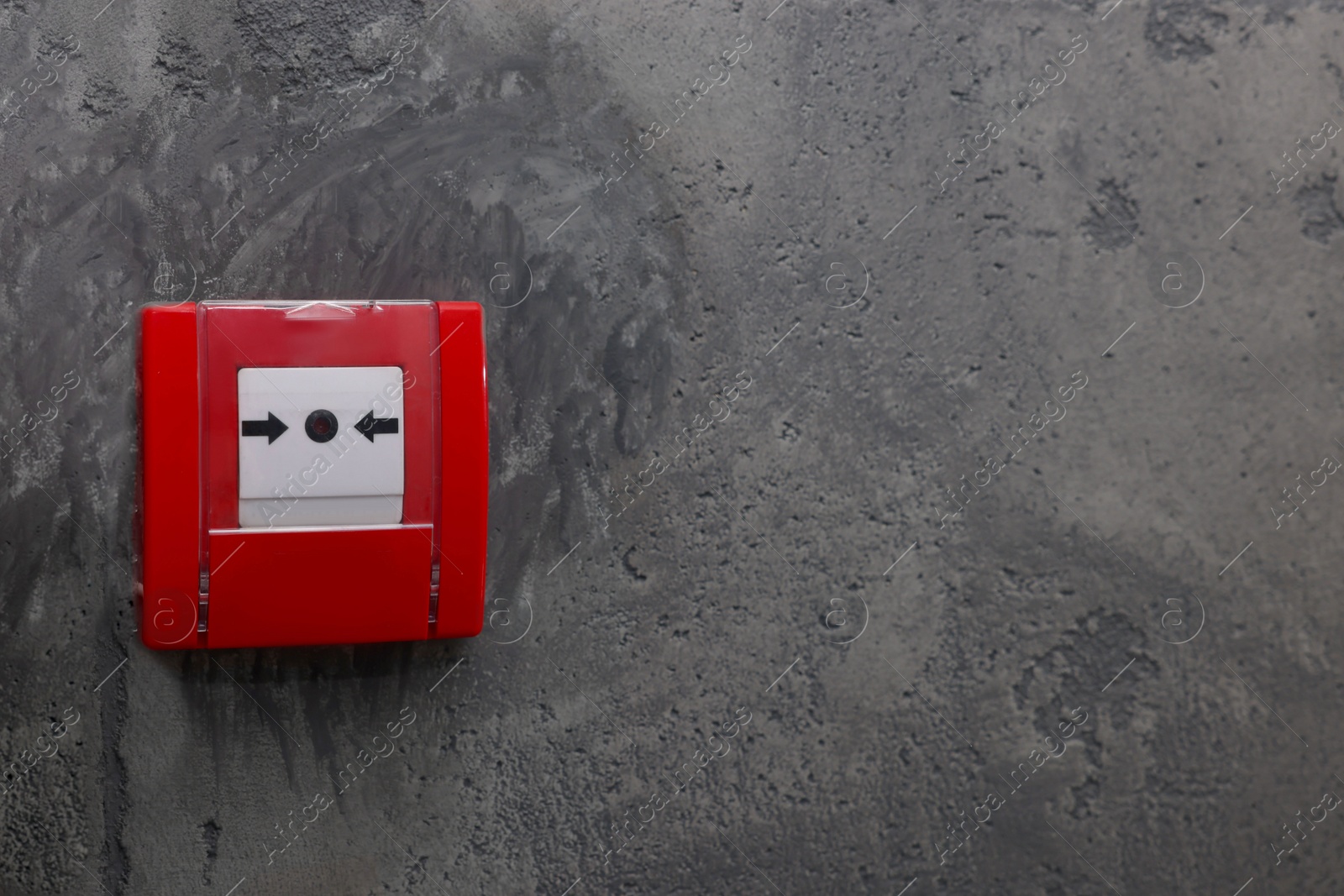 Photo of Fire alarm push button on grey wall, space for text