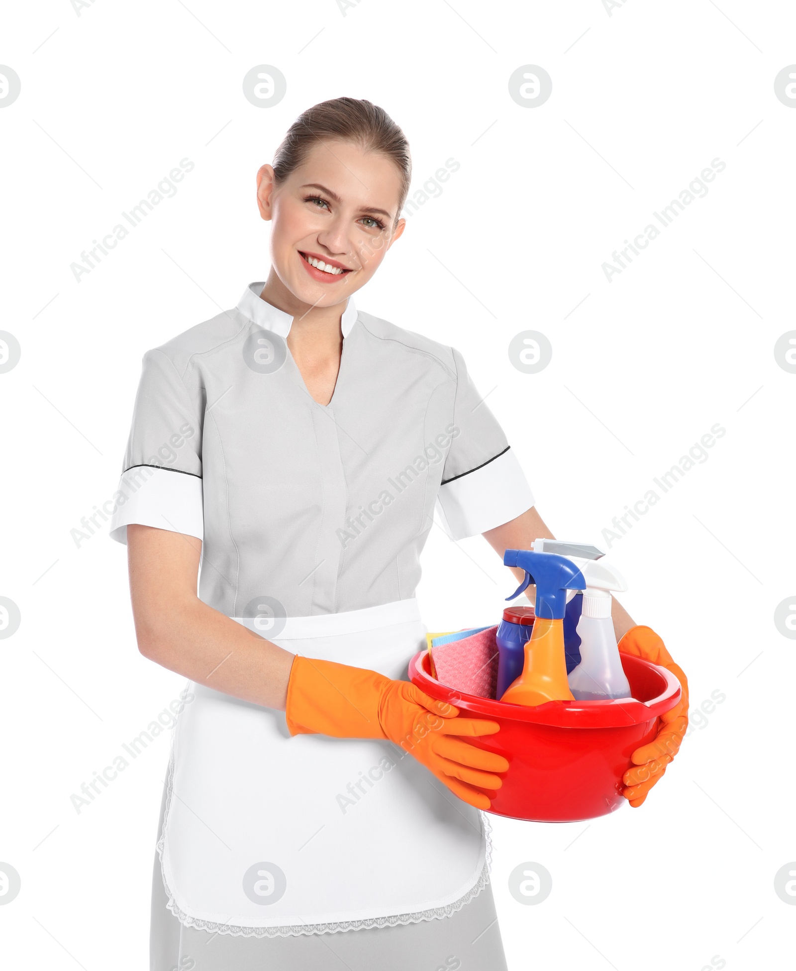 Photo of Young chambermaid holding basin with cleaning supplies on white background