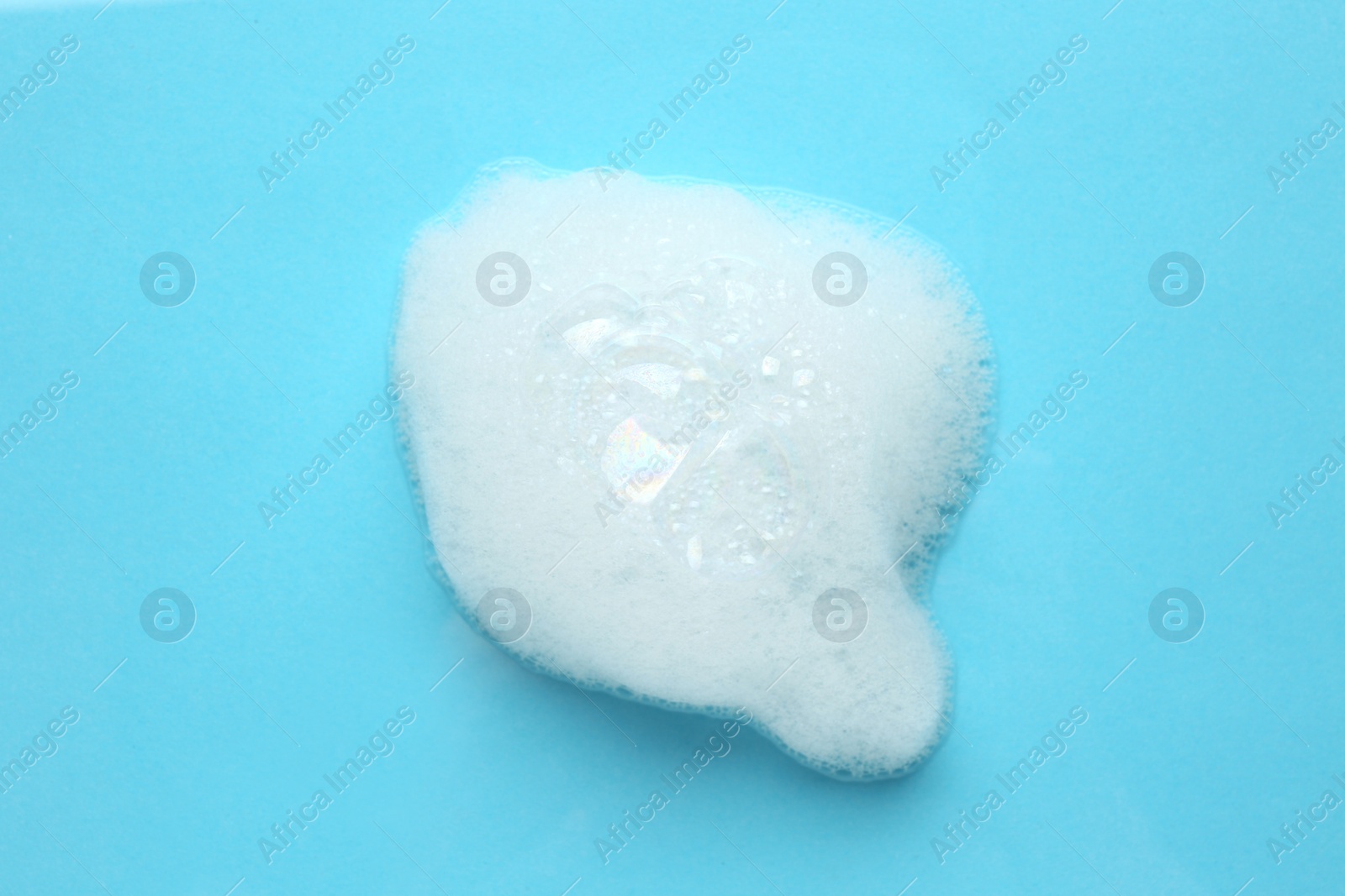 Photo of Drop of bath foam on turquoise background, top view